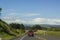 Cars driving on rural asphalt road with vibrant green landscape