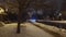 Cars driving slowly, snow covered street in a residential area at night
