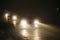 Cars in a fog during night with shining headlights