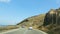 Cars going along curvy coastal highway, view from inside of auto running behind