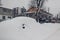 Cars heavily covered with snow during snowfall in city. Automobiles stuck in heaps after winter blizzard