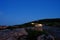 cars leaving the top of Cadillac Mountain after sunset with light streaks agains the alpen glow on pink granite boulders