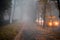 Cars move along an autumn road in conditions of poor visibility. Blurred fog effect. The sidewalk with a pair of walkers is in