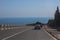 Cars move along a winding road along the sea coast