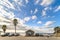 Cars parked around a wooden hut made with dried branches along Sunset beach overlooked by palm trees in Fukuoka.