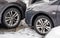 Cars parked with bumpers close to each other, detail on dirty front and tires at snow covered ground