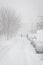 Cars parking under heavy snow on the street. City storm.