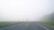 Cars on the road in the fog. Bad weather and dangerous automobile traffic on the road. Light vehicles in fog. Foggy gray