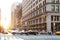 Cars speed down 5th Avenue with the glow of sunlight reflecting on the background buildings in Manhattan