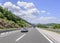 Cars speeding on the Autobahn among mountain scenery.