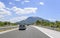 Cars speeding on the Autobahn among mountain scenery.