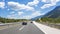 Cars speeding on the Autobahn among mountain scenery.