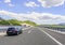 Cars speeding on the Autobahn among mountain scenery.