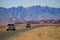 Cars with tourists travel among the stunning landscapes of the Namib Desert, surrounded by mountains