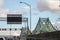 Cars & truck traffic on the highway of Jacques Cartier bridge with its logo, in the direction to Montreal.