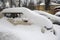 Cars under a large layer of snow in a parking lot