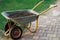 Cart with soil on paving slabs next to green lawn. Wheelbarrow with earth, for gardening