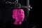 A cartesian 3D-printer manufactures a humanoid head from bright pink plastic.