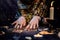 Cartomancy. A fortune teller reads Tarot cards. On the table are candles and fortune-telling objects and sparks. Hands close up.