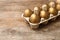 Carton with golden eggs on wooden table