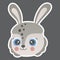 Cartoon cute face of smiling little hare with big eyes, ruddy cheeks, white outline on a square dark brown background. For sticker