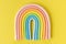 Cartoon edible rainbow made of confectionery mastic on the yellow background.