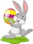 Cartoon little rabbit holding easter egg in the grass
