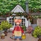 Cartoon smiling male gardener standing in the yard of the house