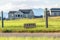 Carts sign on a grassy terrain by a road with homes and mountain background