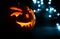 Carved face of pumpkin glowing on Halloween on blue bokeh light background