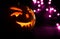 Carved face of pumpkin glowing on Halloween on purple bokeh light background