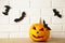 Carved glowing pumpkin and black bats on light background. Halloween celebration