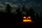 Carved halloween pumpkin jack-o-lantern with burning candles glows in a darkness. Spooky landscape