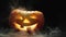 Carved Halloween pumpkin jack-o-lantern with candles in it on dark table with white smoke. The light is blinking.