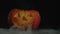 Carved Halloween pumpkin jack-o-lantern with candles in it on dark table with white smoke. The light is blinking. Close up.