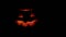 Carved Halloween pumpkin lights inside with flame on a black background with lighted candles close up. slowmotion