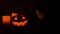 Carved Halloween pumpkin lights inside with flame on a black background with lighted candles close up. slowmotion