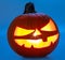 Carved pumpkin for Halloween jack-o\\\'-lanterns with scary smiles and burning candle inside isolated on blue background