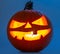 Carved pumpkin for Halloween jack-o\\\'-lanterns with scary smiles and burning candle inside isolated on blue background