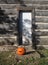 Carved Pumpkin sits on a Door Step of a Log Cabin