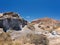 A carved rock sculpted by wind erosion against background of deep blue sky. Black lava gravel