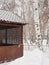 carved wooden outdoor porch terrace in a winter park on a background of snowy trees.  mobile photography