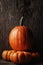 Carving pumpkin on top of three decorative mini pumpkins, Vertical format with warm side light and copy space