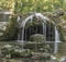 Cascade of the river in the form of a small waterfall. Green natural background.