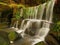 Cascade of small weir on mountain stream, water is running over sandstone blocks and bubbles create milky water.