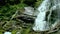 Cascade waterfall splash on stones in forest among mountains.