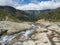 Cascade of wild Freigerbach stream in alpine landscape valley, snow-capped mountain peaks.Tyrol, Stubai Alps, Austria