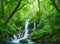 A cascading waterfall hidden within a lush, emerald-green rainforest