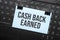 cash back earned inscription on white paper note on laptop keyboard. Closeup message