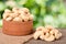 Cashew nuts in a wooden bowl on the board with blurred garden background